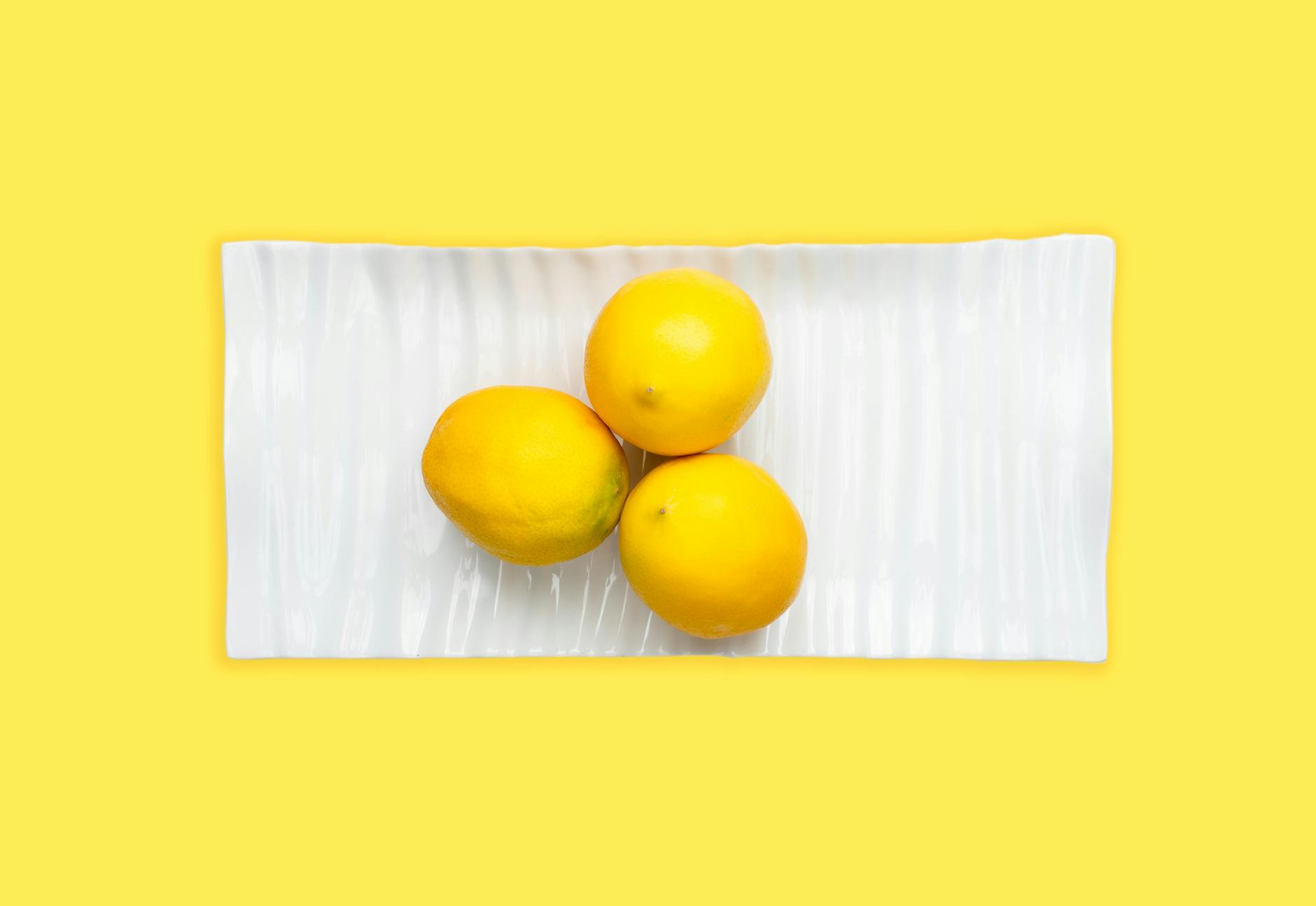 Fresh lemons on white plate with yellow background, symbolizing renewed sensation and fresh approach to pleasure
