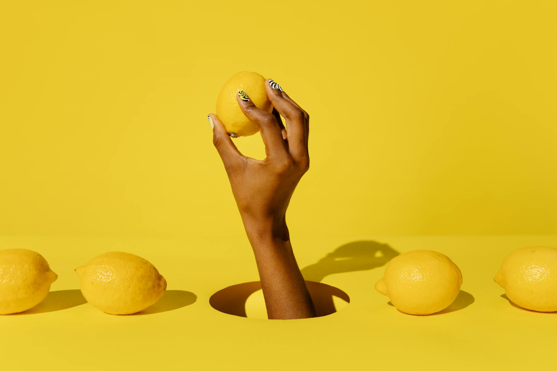 A fresh lemon held against a bright yellow background, symbolizing sensation awakening and recovery