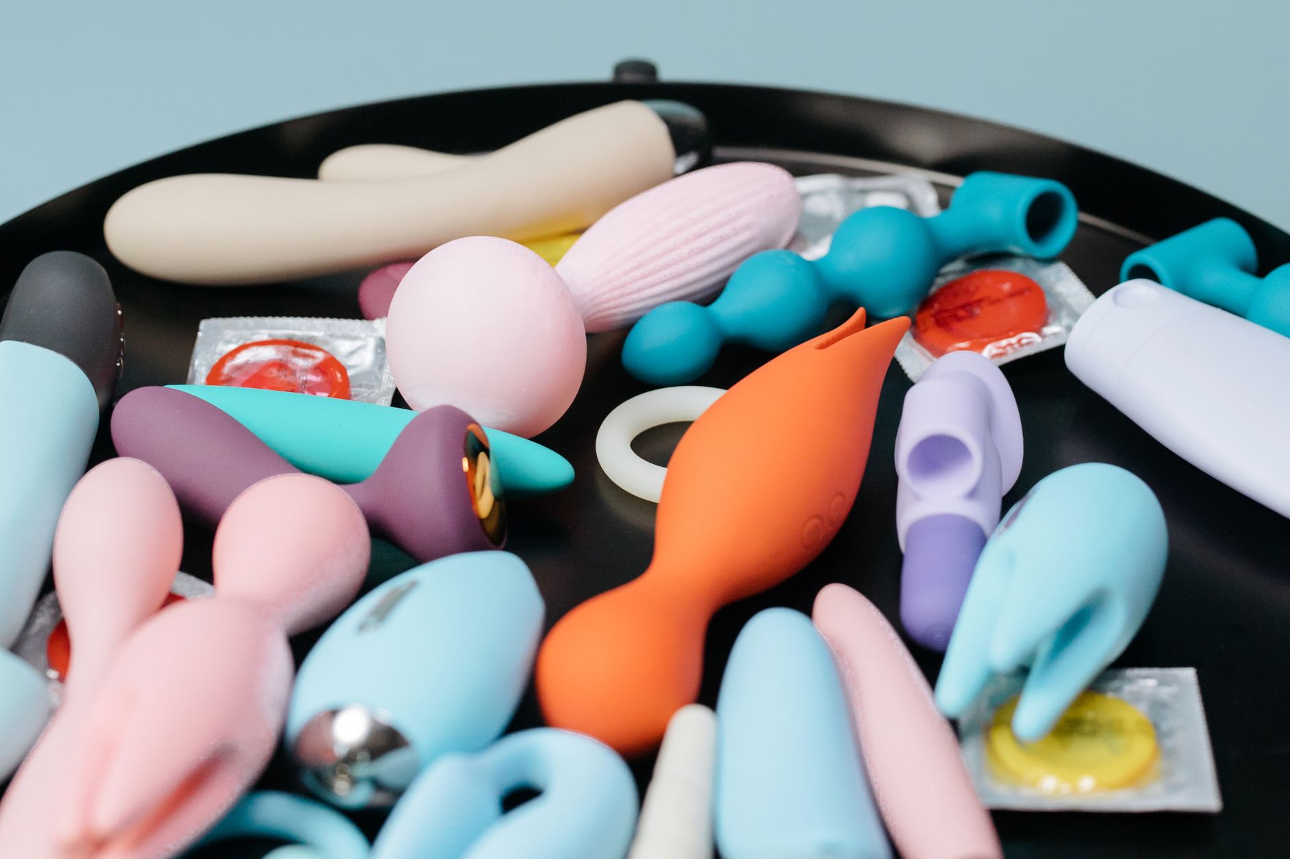 A vibrant collection of various adult toys on a black tray, featuring diverse shapes and colors.