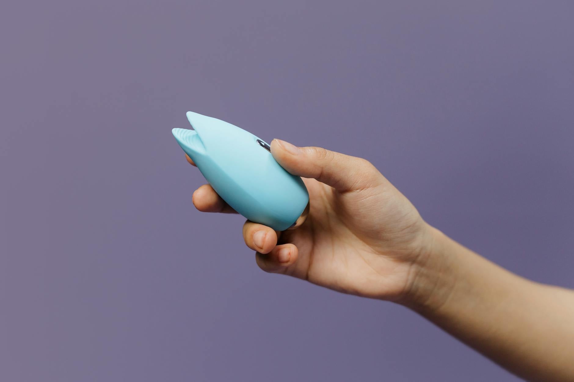 Lemon clitoral vibrator held in hands against purple background, representing solo and partnered pleasure