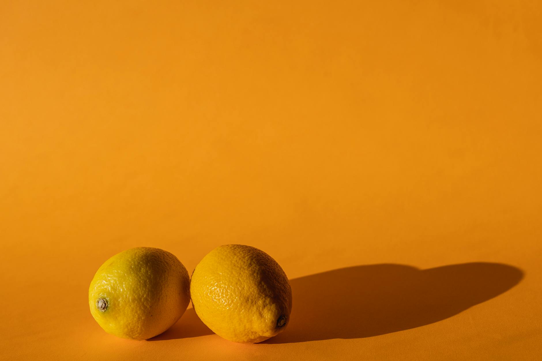 A close-up of a hand holding an orange vibrator against a minimalistic purple backdrop, showcasing modern sensuality